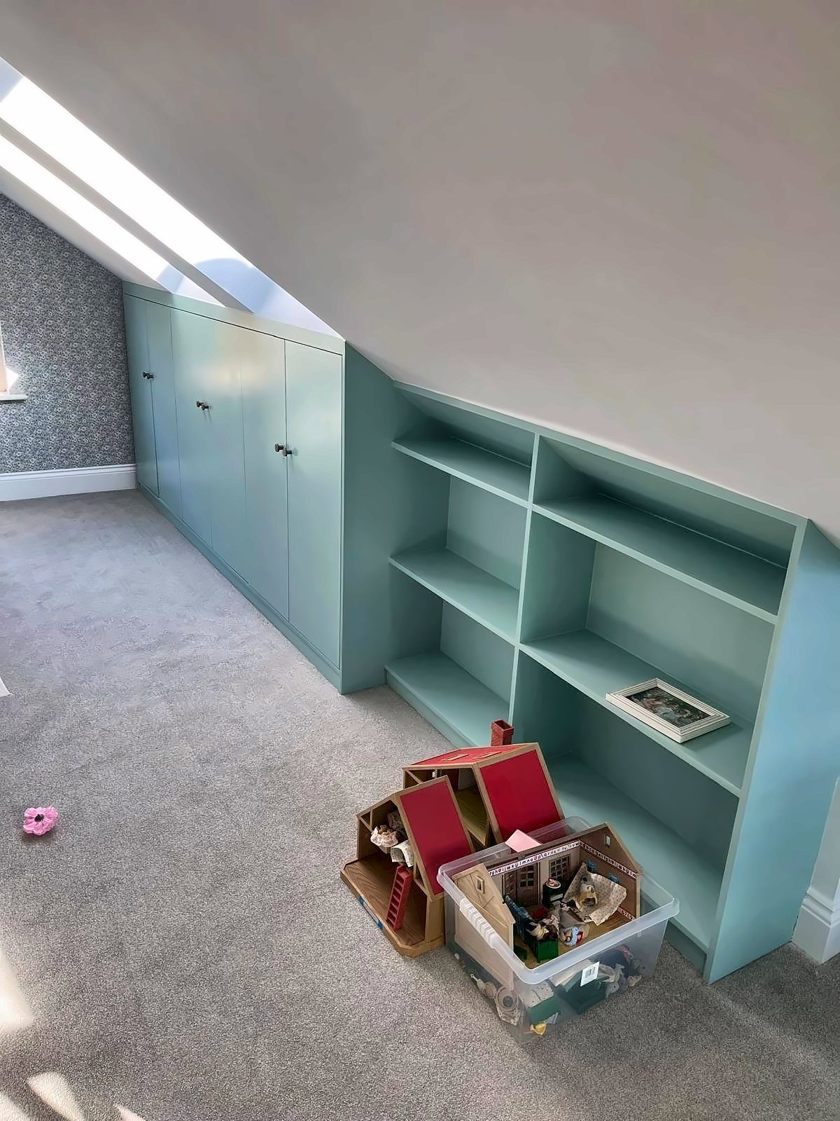 Built-in cupboards and shelving fitted under a sloping attic ceiling