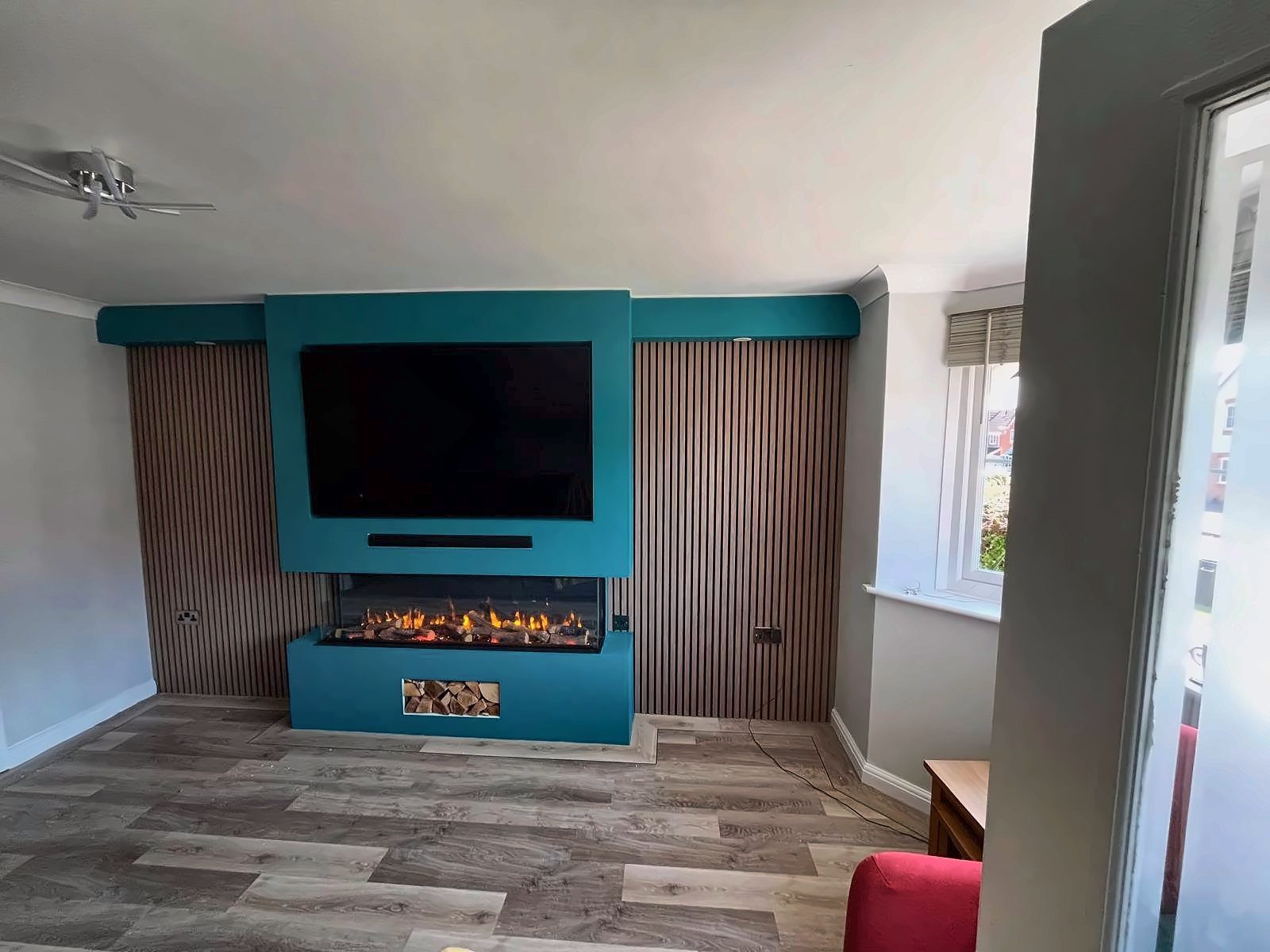 Teal media wall with a built-in TV recess and fire